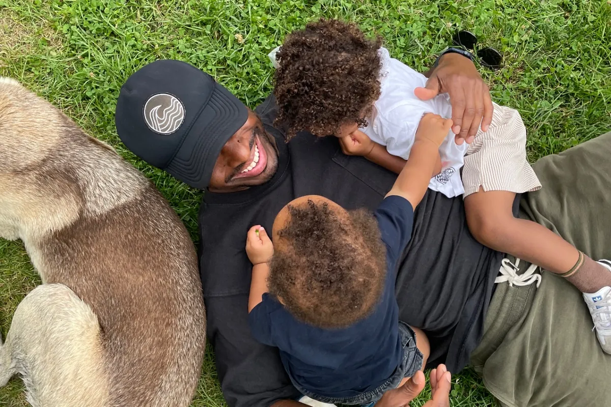 Adrian LeRoy in the grass with his two young sons and the family dog