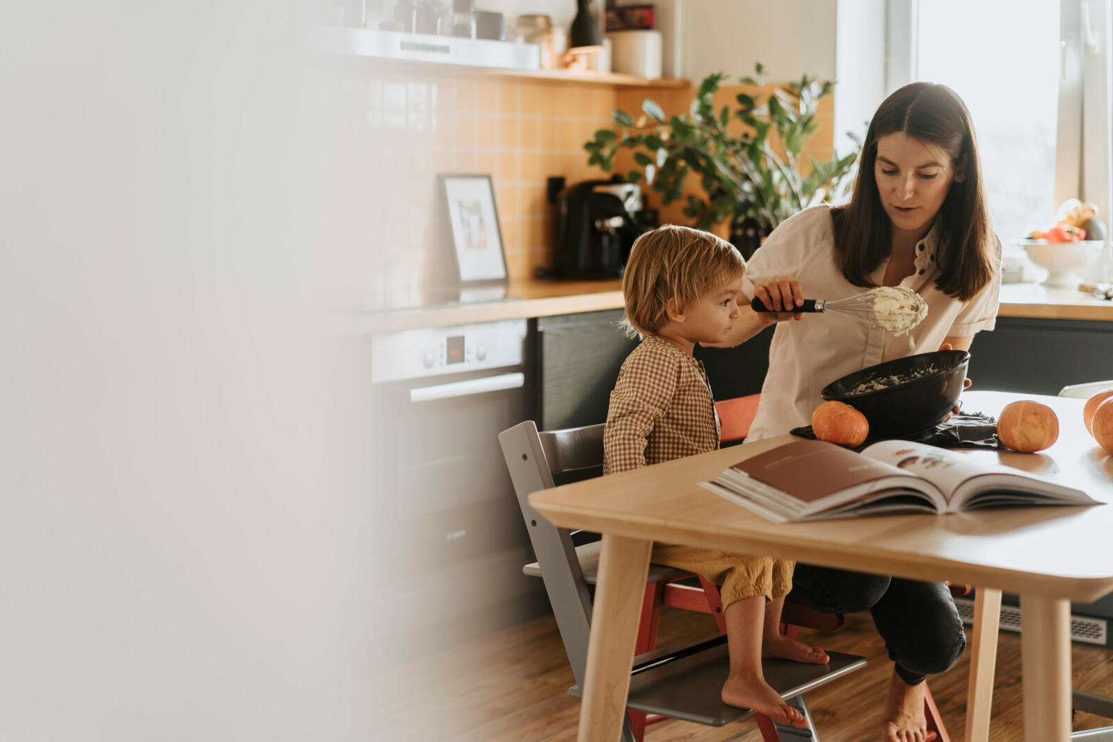 Mother and toddler baking together at a kitchen table